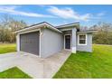 Single-story home showcasing gray exterior, gray garage door, a walkway, and a green lawn at 47 Sequoia Loop, Ocklawaha, FL 32179