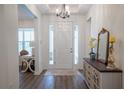 Inviting entryway with light hardwood floors, white door with glass panels and a decorative mirror and flowers at 6367 Sw 70Th Cir, Ocala, FL 34474