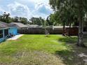 Sprawling backyard features a tall wooden fence, large shade trees, and playset at 6950 Se 124Th Ln, Belleview, FL 34420