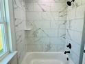 Bathroom features a tub with white marble tiling and black fixtures next to a bright window at 8295 Se 159Th Ln, Summerfield, FL 34491