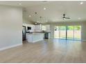 Spacious living room featuring an open kitchen, stainless appliances, granite countertops, and sliding glass doors at 8295 Se 159Th Ln, Summerfield, FL 34491