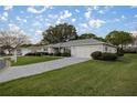 Single-story home with a lush lawn, manicured landscaping, paved driveway, and attached two car garage at 9033 Se 136Th Loop, Summerfield, FL 34491