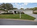 Inviting single-story home with a well-manicured lawn, lush landscaping, a two-car garage and a paved driveway at 9033 Se 136Th Loop, Summerfield, FL 34491