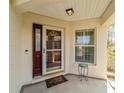 Inviting front porch featuring a decorative welcome mat, glass storm door, and exterior window at 9126 Sw 102Nd Cir, Ocala, FL 34481