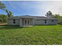 A view of the back of the home featuring a modest backyard and a covered patio area at 96 Fisher Way Trl, Ocklawaha, FL 32179