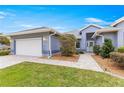 Beautiful home exterior showcasing well-kept lawn, gray paint, paver driveway, and manicured landscaping at 11593 Sw 75Th Cir, Ocala, FL 34476