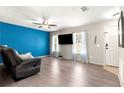 Open-concept living room features wood-look floors, a vibrant accent wall, and a modern ceiling fan at 13 Pine Course Radl, Ocala, FL 34472