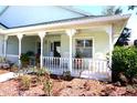 Charming front porch with white railings, ceiling fans, and views of the beautifully landscaped garden at 11091 Sw 73Rd Ct, Ocala, FL 34476