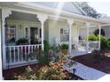 Inviting front porch features decorative columns, comfortable seating, and a landscaped garden at 11091 Sw 73Rd Ct, Ocala, FL 34476