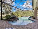 Beautiful screened-in pool area featuring a rock waterfall and well-maintained brick patio at 3848 Nw 85Th Ter, Ocala, FL 34482