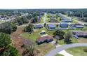 Aerial view of a home nestled in a quiet neighborhood surrounded by lush greenery and blue skies at 4858 Sw 143Rd Loop, Ocala, FL 34473