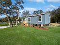 Charming single-story home with blue siding, landscaped yard, and cozy front porch at 11745 Nw 15Th Lane, Ocala, FL 34482