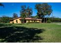 Picture of a home with a vast front yard, set against a backdrop of tall trees and a clear blue sky at 1255 Ne 70Th St, Ocala, FL 34479