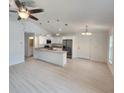 Open concept living space with white walls, vaulted ceiling, fan, and views of the modern kitchen at 209 Sw Winding Hills Rd, Dunnellon, FL 34431