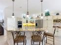 Open kitchen with granite countertops, stainless steel appliances, and a breakfast bar with stylish pendant lighting at 383 Harlow Ln, The Villages, FL 32163