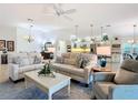 Bright living room featuring neutral-toned sofas, elegant lighting, and seamless flow into the kitchen at 383 Harlow Ln, The Villages, FL 32163