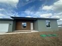 Modern home with a two-car garage, light green stucco, and a decorative wood plank front in a grassy neighborhood at 4501 Sw 110Th Ln, Ocala, FL 34476