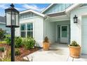 Inviting front entrance with decorative potted plants and charming details on this light-colored house at 503 Verlander St, The Villages, FL 34762