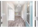 Bright entryway featuring wood-look flooring, a modern chandelier, and a blue glass-paneled front door at 5910 Sw 111Th Place Rd, Ocala, FL 34476