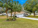 Charming single-story home featuring a well-manicured lawn, palm trees, and a decorative driveway at 6450 Sw 83Rd Ln, Ocala, FL 34476