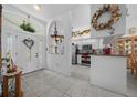 Bright foyer with tiled floors, features a decorated glass front door and an arched doorway to the kitchen at 7178 Sw 113Th Loop, Ocala, FL 34476