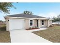 Beautifully landscaped home showcasing a two-car garage, modern neutral exterior, and newly installed front door at 13272 Sw 112Th Pl, Dunnellon, FL 34432