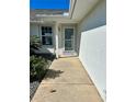 A close-up of the front porch with a storm door, window, and manicured garden along the side at 17799 Se 125Th Cir, Summerfield, FL 34491