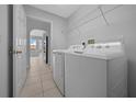 Bright laundry room featuring a modern washer and dryer set, tile flooring, and convenient overhead shelving at 17799 Se 125Th Cir, Summerfield, FL 34491