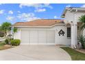 Spacious two car garage and driveway; landscaped with green lawn and bushes at 2399 Nw 53Rd Avenue Rd, Ocala, FL 34482