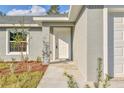 Inviting front entrance featuring a white door, textured gray exterior, and manicured landscaping at 7772 Sw 146Th Lane Rd, Ocala, FL 34473