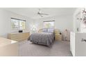 Bright main bedroom featuring neutral carpeting, a ceiling fan, and ample natural light from two windows at 17421 Se 107Th Ct, Summerfield, FL 34491