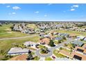 An aerial view of a neighborhood shows many single-story homes, green golf course, and clear blue skies at 17818 Se 120Th Ct, Summerfield, FL 34491