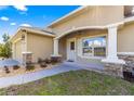 Covered front porch featuring stone columns, manicured landscaping, and a welcoming entrance at 20396 Sw 79Th Lane, Dunnellon, FL 34431