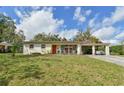 Well-maintained single-story home with a covered porch, adjacent carport, and a neatly manicured front lawn under a blue sky at 5812 Luzon Pl, Orlando, FL 32839