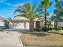 Well-maintained home exterior featuring a three-car garage and lush tropical landscaping at 805 Pickett Rd, The Villages, FL 32163