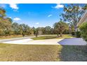 A long driveway leads through a grassy yard to a quiet road surrounded by lush trees at 8126 Sw 105Th Pl, Ocala, FL 34481