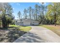 Side view of a modern home featuring a long driveway, attached garage, and a basketball hoop at 18301 Sw 69Th Loop, Dunnellon, FL 34432