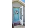 Front entrance featuring a charming blue door adorned with a floral wreath and a decorative welcome mat at 3326 Sw 128Th Street Rd, Ocala, FL 34473