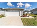 Frontal view of a two-car garage with an expansive concrete driveway and manicured landscaping at 6213 Sw 97Th St, Ocala, FL 34476