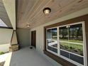 Inviting covered porch with wood ceiling detail and a view of the landscaped yard at 8303 Sw 127 Ave, Dunnellon, FL 34432