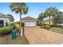 Inviting single-story home featuring a brick driveway, lush landscaping, and a convenient two-car garage at 8669 Sw 88Th Loop, Ocala, FL 34481