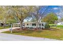 Attractive single-story home boasts a covered carport, a screened-in porch, and a well-maintained front yard with mature trees at 8973 Sw 104Th Pl, Ocala, FL 34481