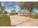 Inviting single-story home with a spacious driveway, a covered carport, and a screened-in porch, perfect for outdoor living at 8973 Sw 104Th Pl, Ocala, FL 34481