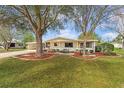 Charming single-story home with a well-manicured lawn, mature trees, and a cozy front porch, creating a welcoming curb appeal at 8973 Sw 104Th Pl, Ocala, FL 34481