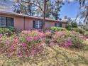 The side yard of the home is decorated with pink azaleas and green bushes at 1034 Ne 11Th St, Ocala, FL 34470