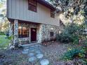 Charming stone-clad home exterior with a covered entrance and stepping stone pathway surrounded by lush greenery at 14540 Ne 250Th Ave, Fort Mc Coy, FL 32134