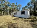 Side view of the manufactured home, boasting a well-maintained lawn and classic white siding at 1921 Nw 120Th Ave, Ocala, FL 34482
