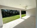 Covered outdoor patio with ceiling fan and spacious concrete platform overlooking the lawn and trees at 5646 Sw 129Th Place Rd, Ocala, FL 34473