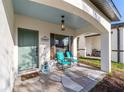Inviting front porch features stylish stone flooring, relaxing chairs, and a decorative green door at 10597 Grand Oaks Blvd, Oxford, FL 34484