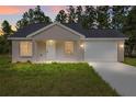 Charming one-story home with inviting front porch and attached garage, beautifully lit at dusk at 127 Sw Alvarez Rd, Dunnellon, FL 34431